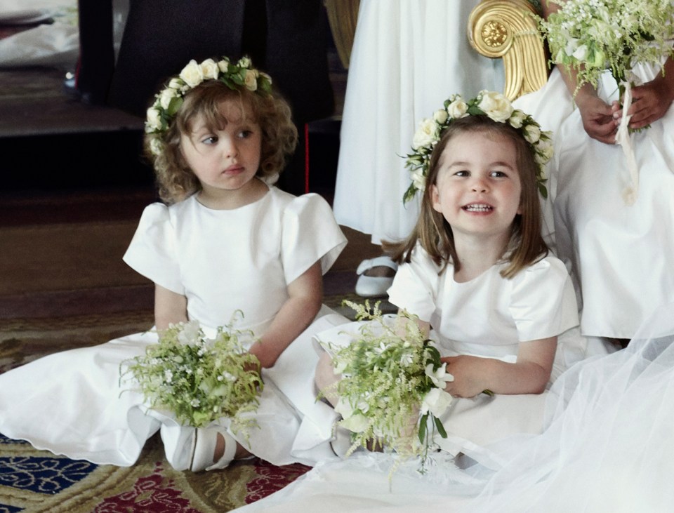 Princess Charlotte and another young girl in white dresses and flower crowns at a wedding.