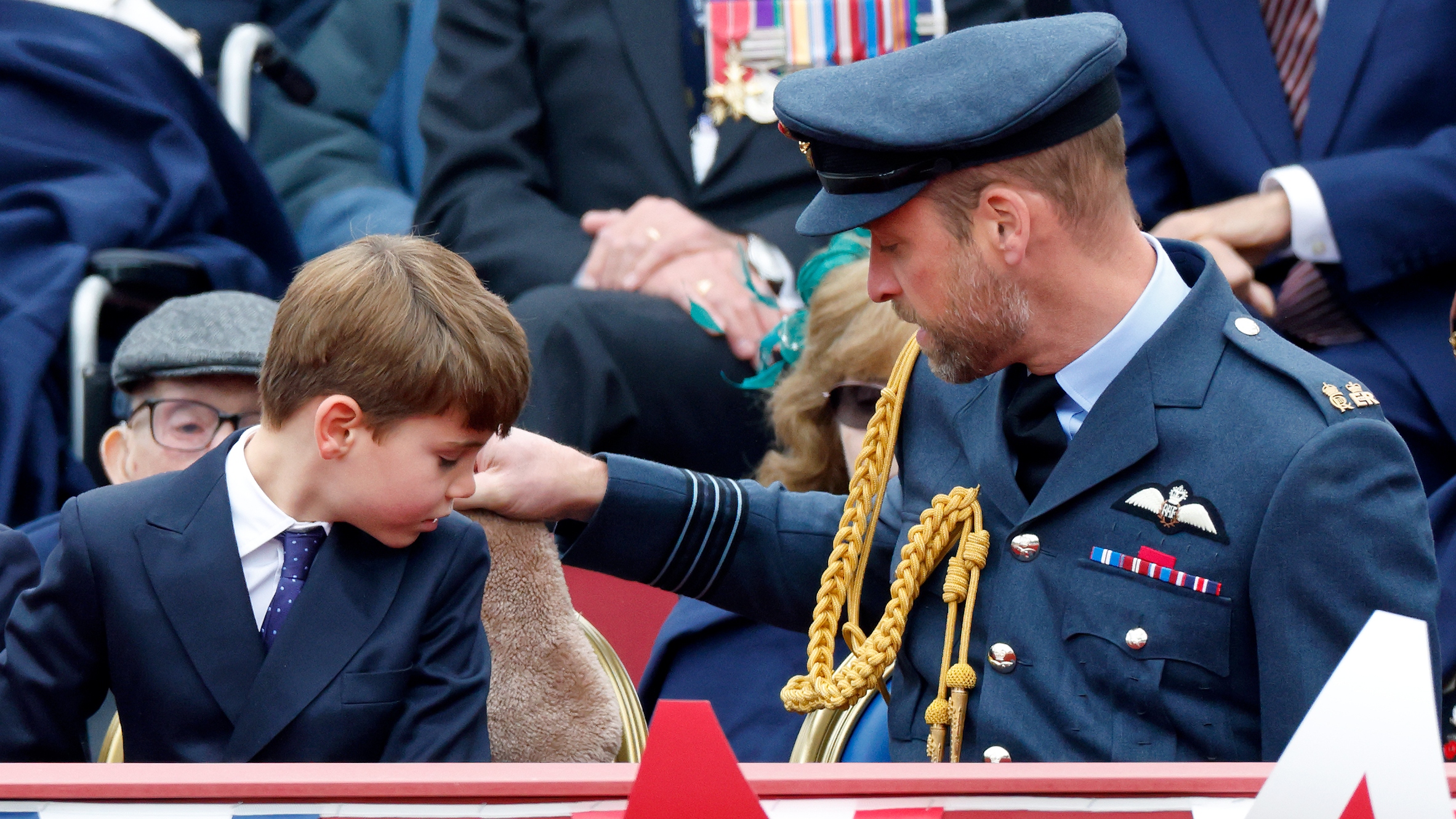 Prince Louis looks behind him as Prince William adjusts the position of his hot water bottle as they attend a military procession to mark the 80th anniversary of VE Day on May 5, 2025