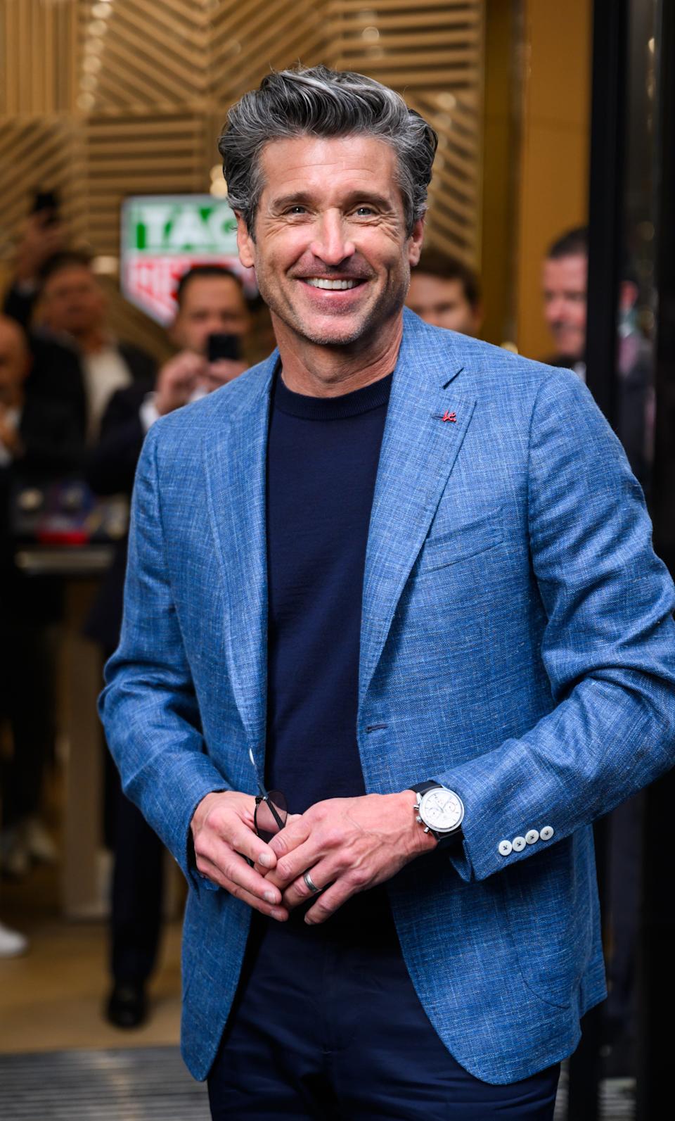 Patrick Dempsey smiling at an event, surrounded by attendees in the background