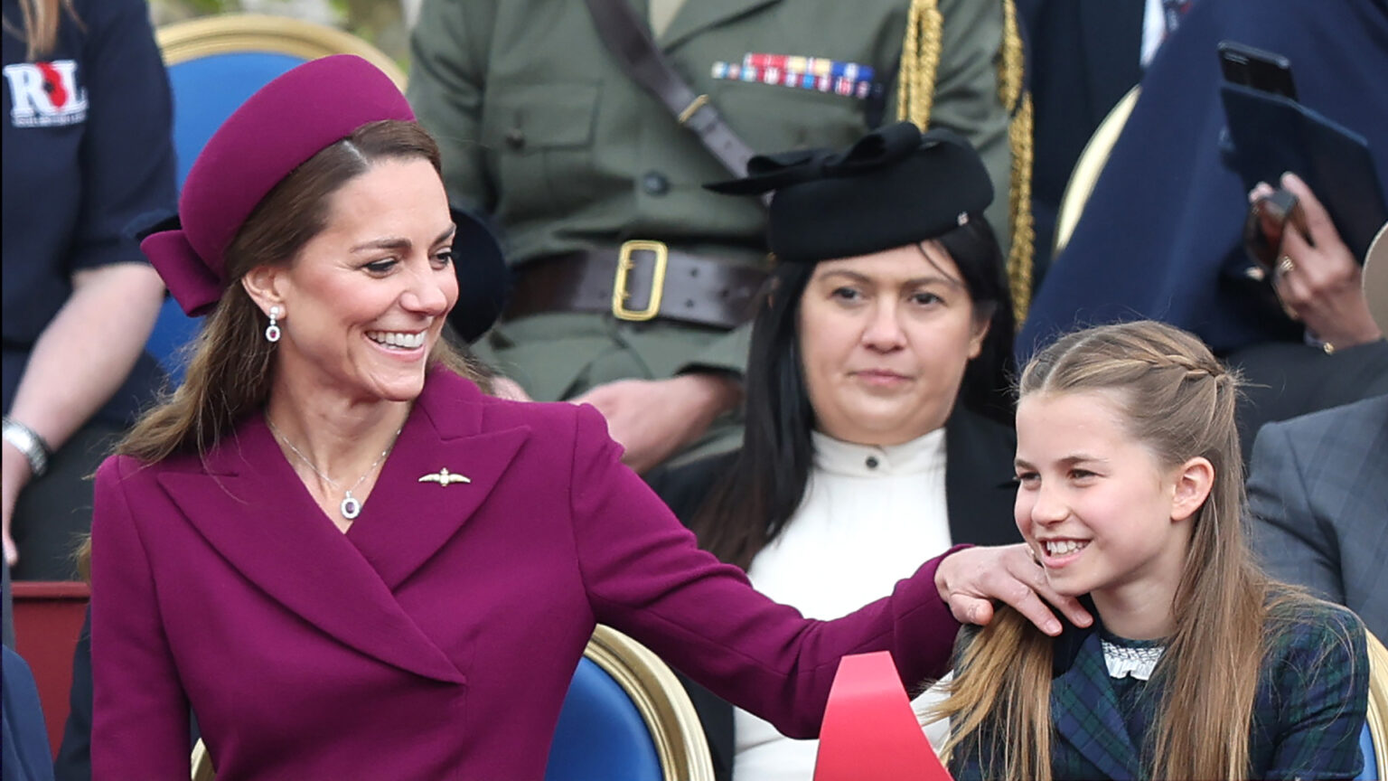 Princess Charlotte and Princess Kate Follow the Same Fashion Philosophy During Surprise Appearance From Wales Kids Princess Kate putting her hand on Princess Charlotte's shoulder sitting at VE Day event