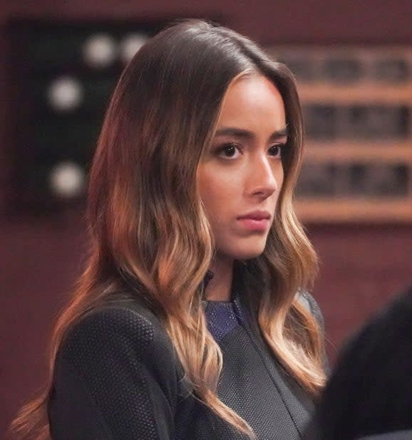 Woman in a patterned, long-sleeve top listening intently to a person with their back turned.