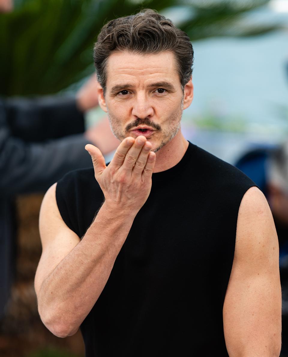 Pedro Pascal playfully blowing a kiss at the camera at an outdoor event