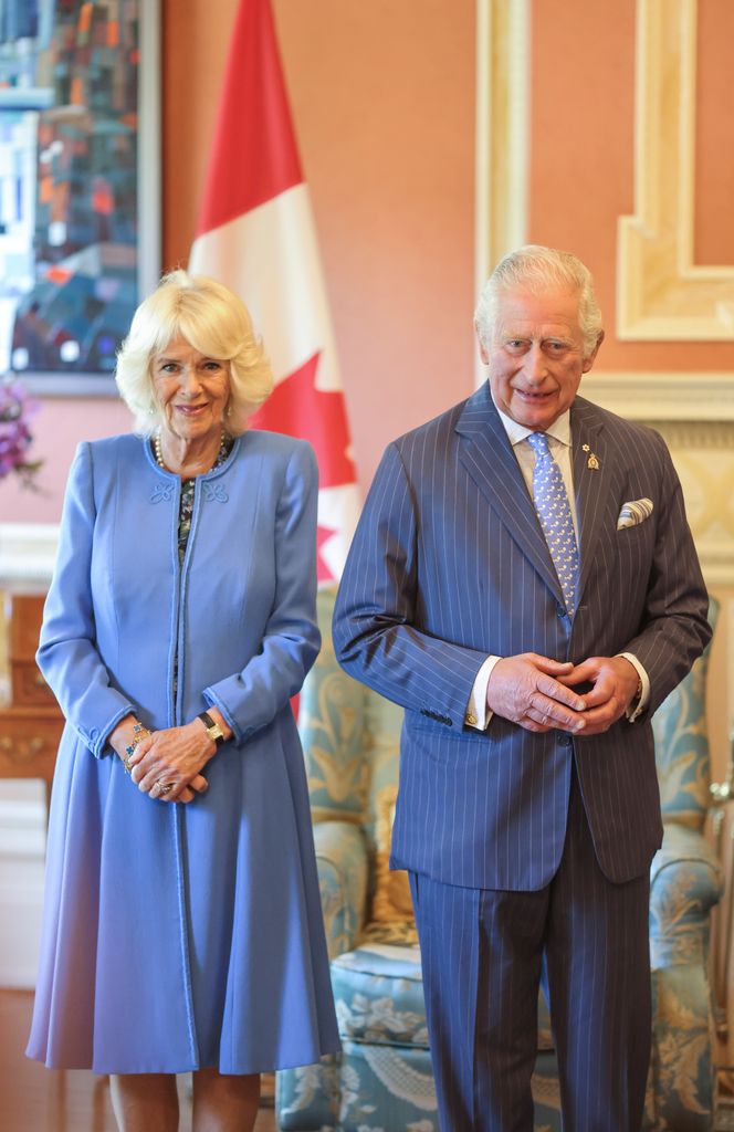 Charles and Camilla standing in front of Canadian flag