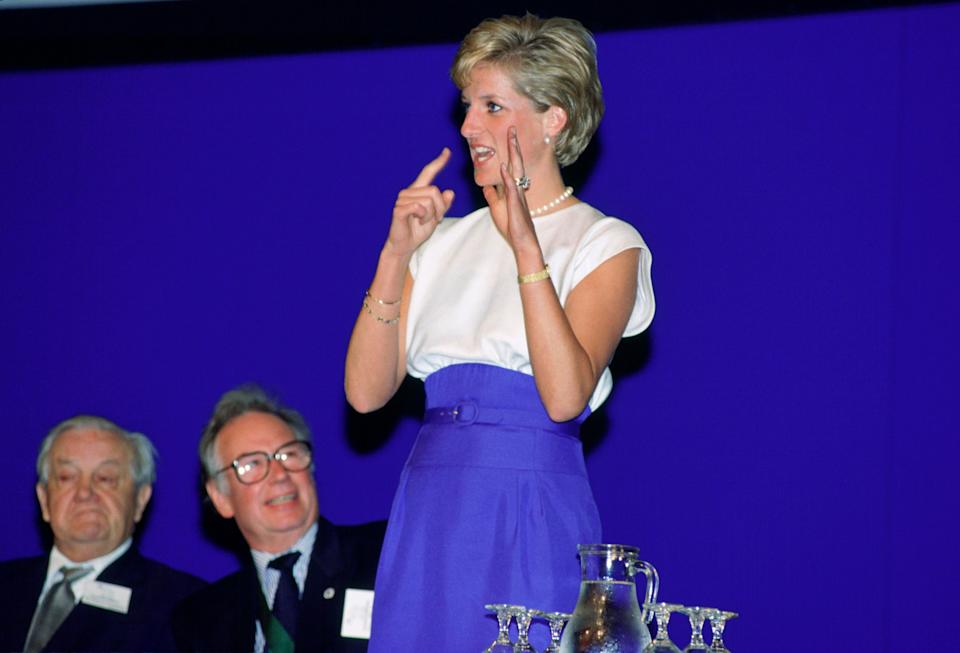 Princess Diana wearing a blue and white dress using sign language