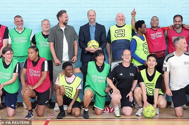 Britain's William, Prince of Wales with Street Soccer Scotland founder and CEO David Duke pose with football coaches and players during a visit