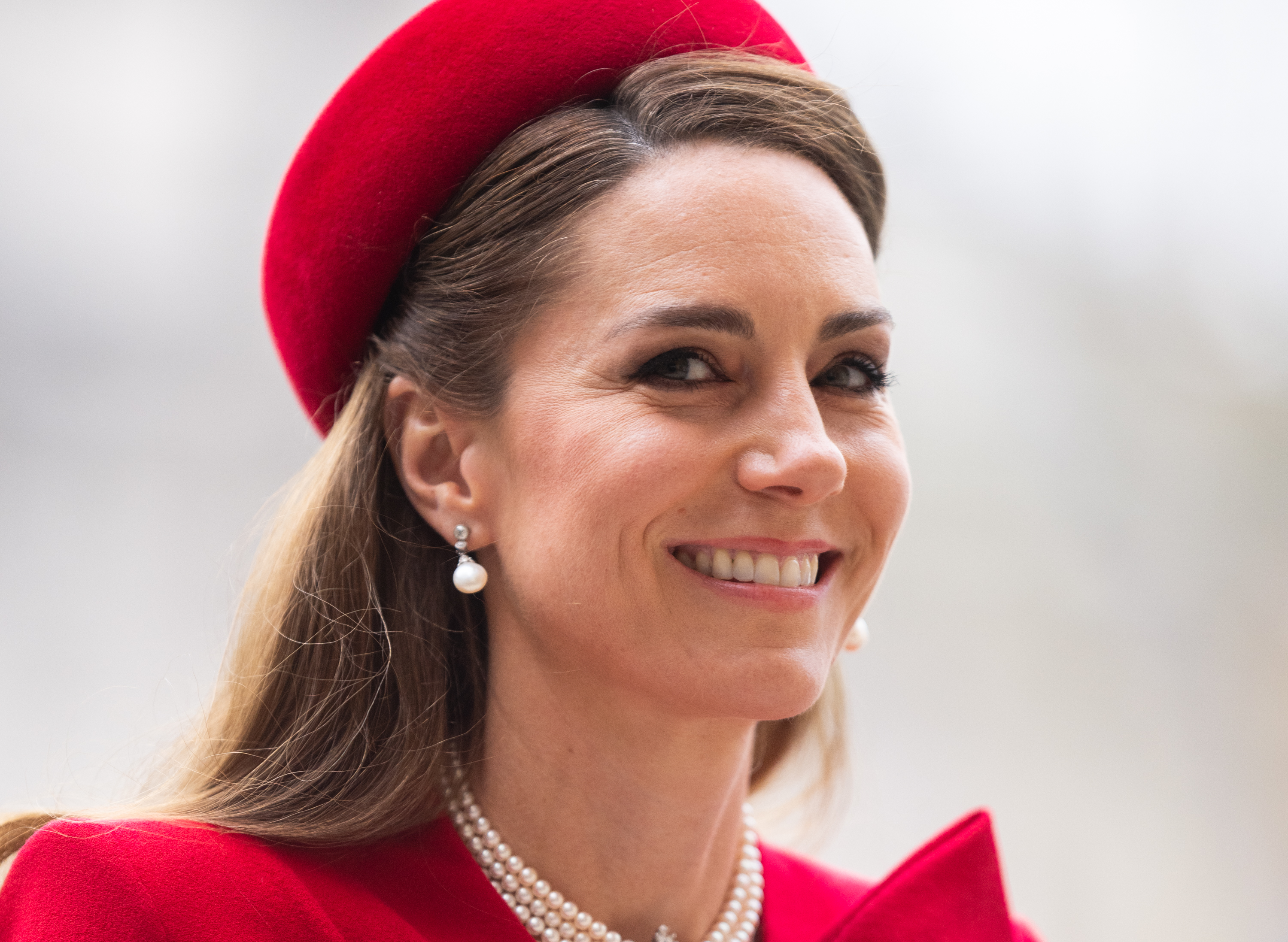 Kate Middleton wearing a red hat and dress with pearls