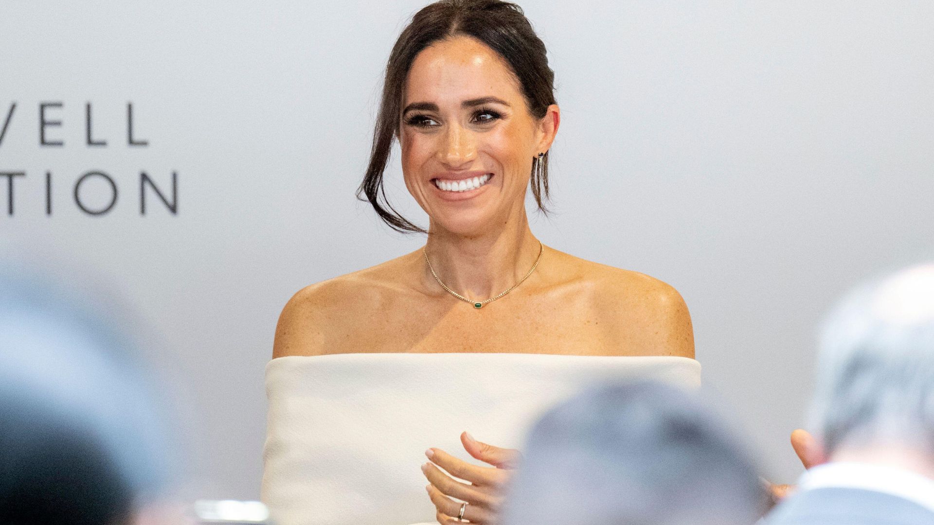 Meghan Sussex smiles in a white strapless dress