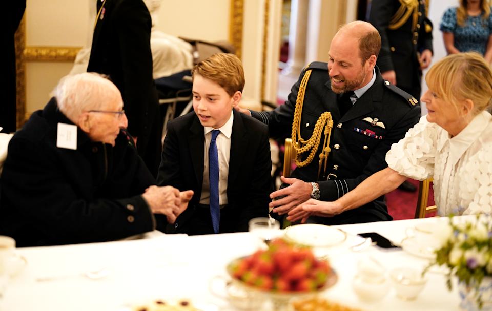 Prince George and Prince William talking to an elderly man at a VE Day tea party