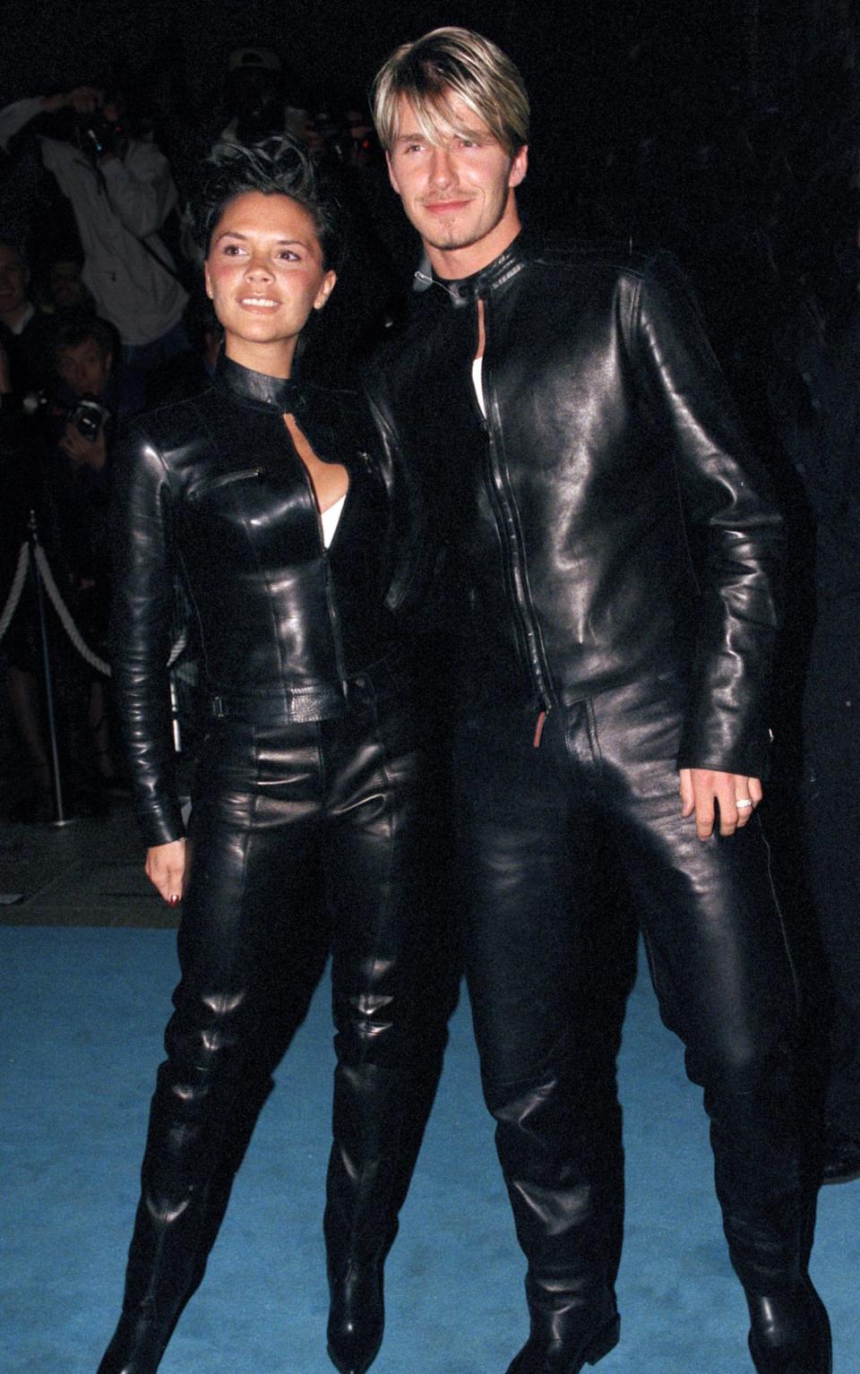 David and Victoria Beckham attend the opening of a Versace store in London wearing matching black leather jumpsuits in 1999
