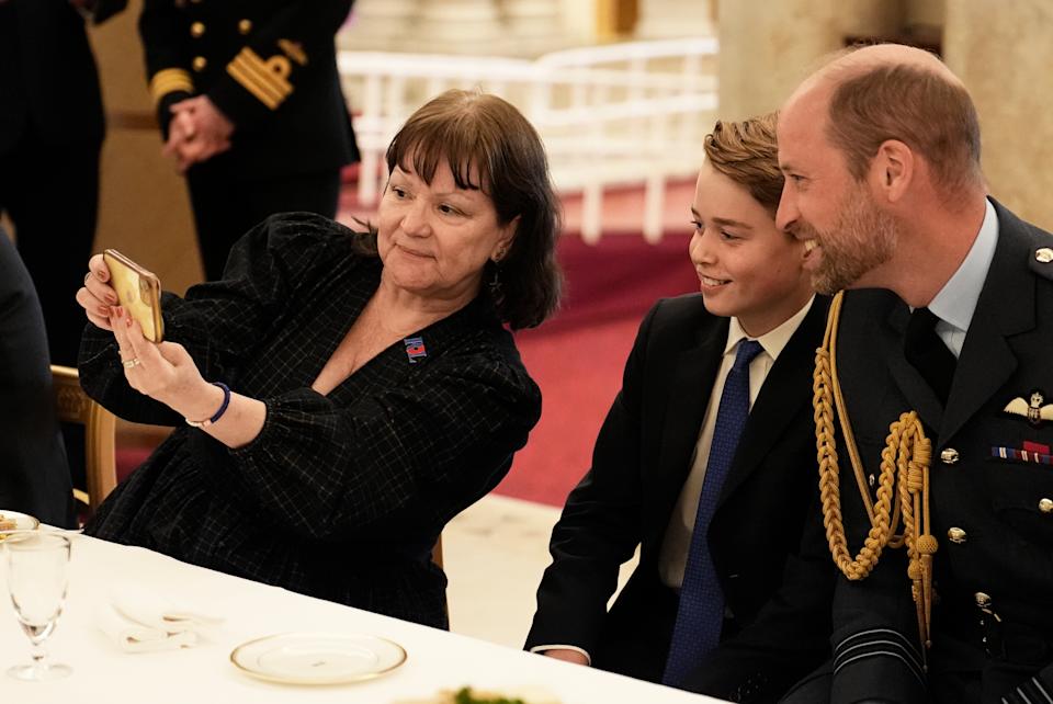 Prince George and Prince William taking a selfie with a woman at a VE Day party