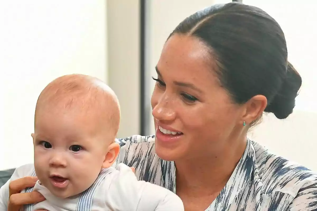 Close-up of Meghan Markle smiling while holding her son, Archie, in her arms.