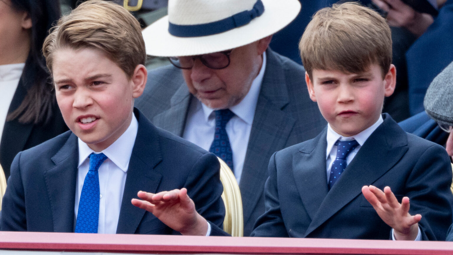 Prince Louis Hilariously Imitates Big Brother Prince George’s Pre-Teen Hair Flip at VE Day Parade Prince George and Prince Louis sitting at the VE Day 80th parade