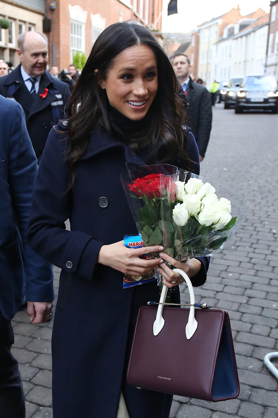 Meghan Markle carrying a Strathberry tote and flowers in 2017