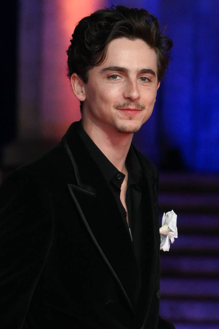 Person in formal black velvet suit with white boutonniere, at an event