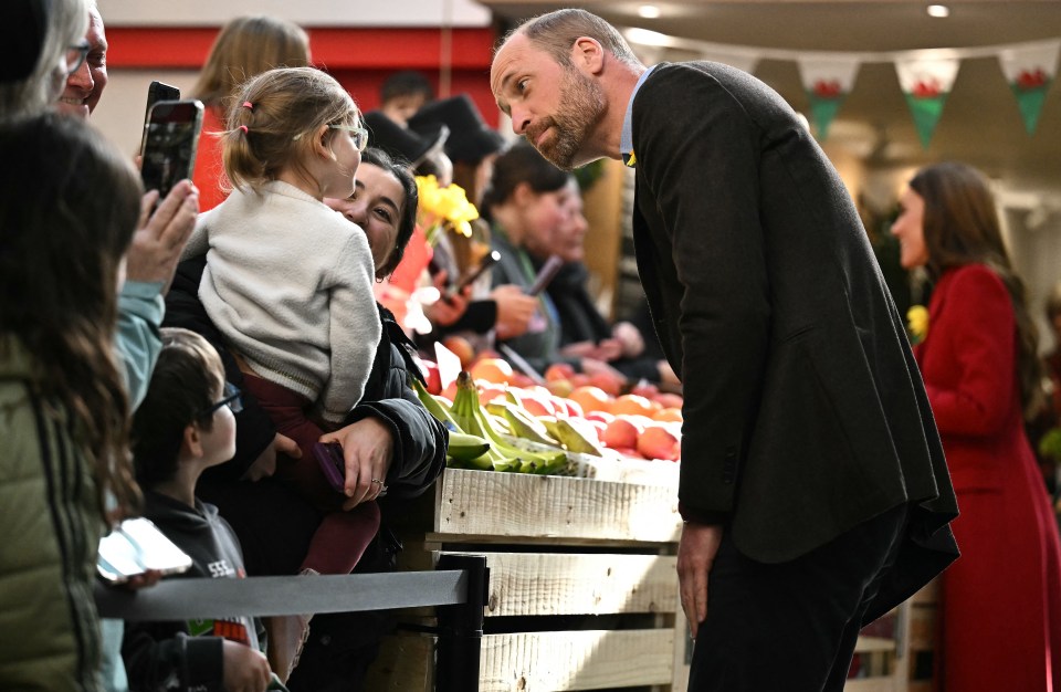 Prince William speaking with well-wishers at a market.