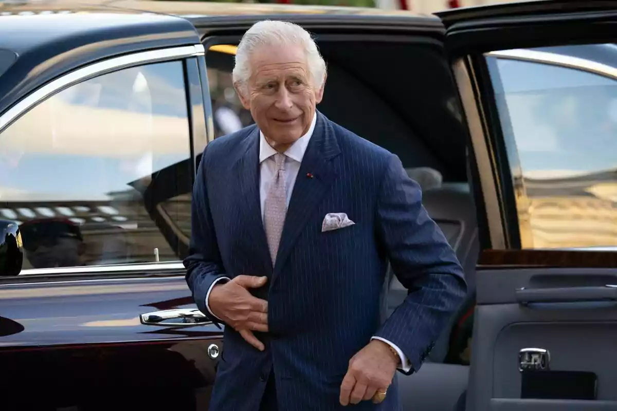 Carlos III in a blue striped suit gets out of an elegant car.