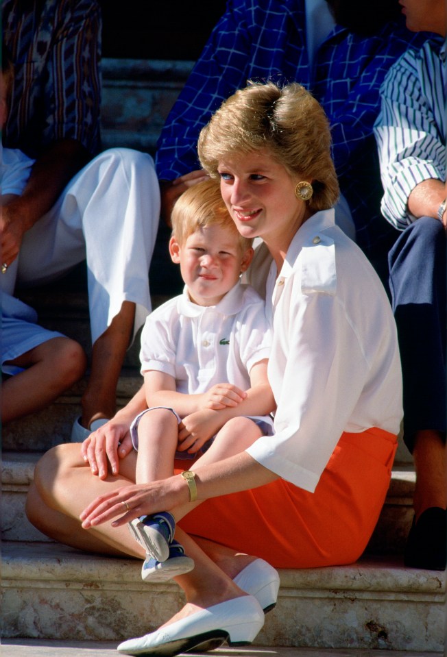 Princess Diana sitting on steps with Prince Harry on her lap.