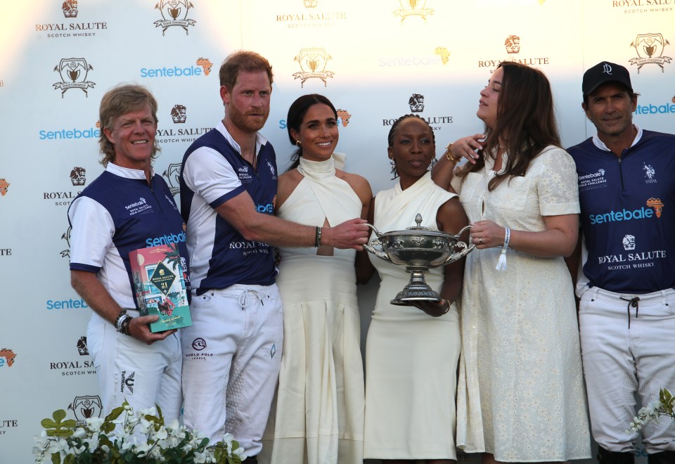 The Duchess of Sussex presents a trophy to her husband, the Duke of Sussex, at a polo match.