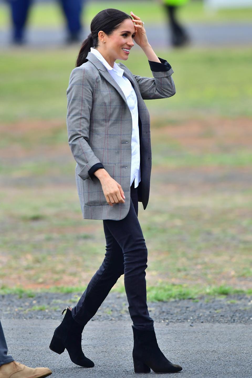 Meghan Markle wearing black jeans and a gray blazer walking outside in Australia