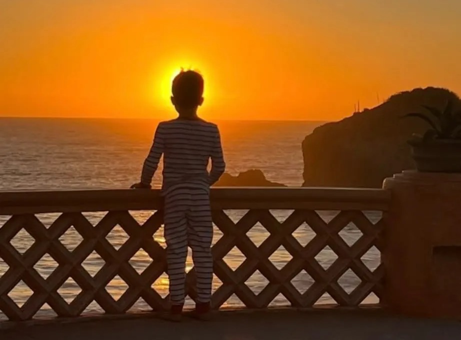Child watching sunset over ocean.