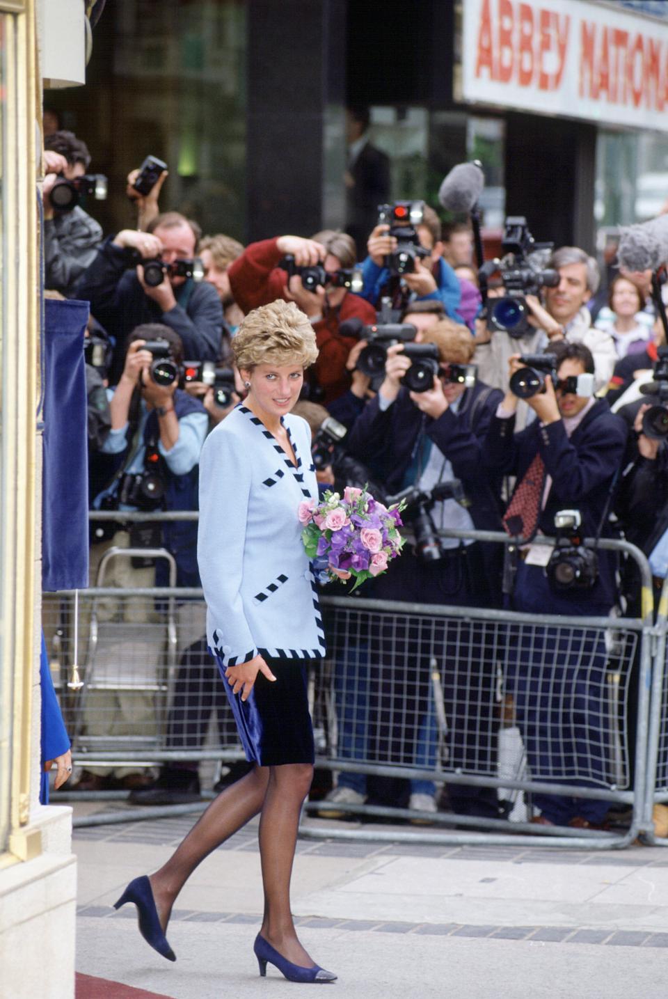 Princess Diana walking in front of a crowd of photographers