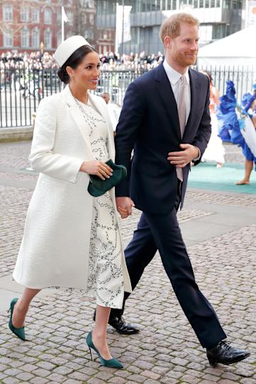 Meghan Markle wearing a white coat and hat walking with Prince Harry at Westminster abbey