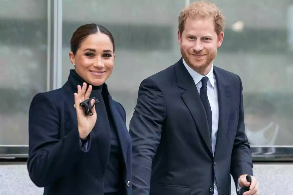 A formally dressed couple smiles as they walk outdoors.