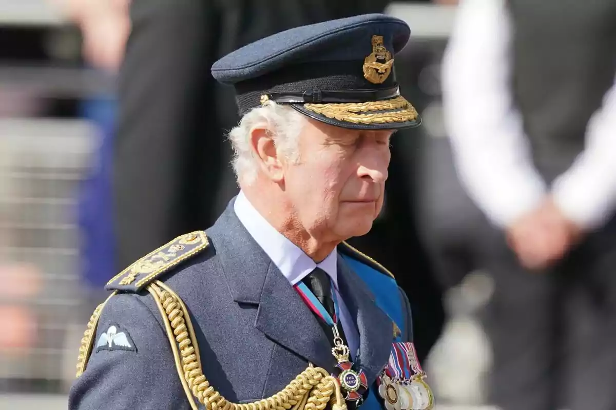 A man in a blue military uniform and a cap decorated with medals and golden cords.