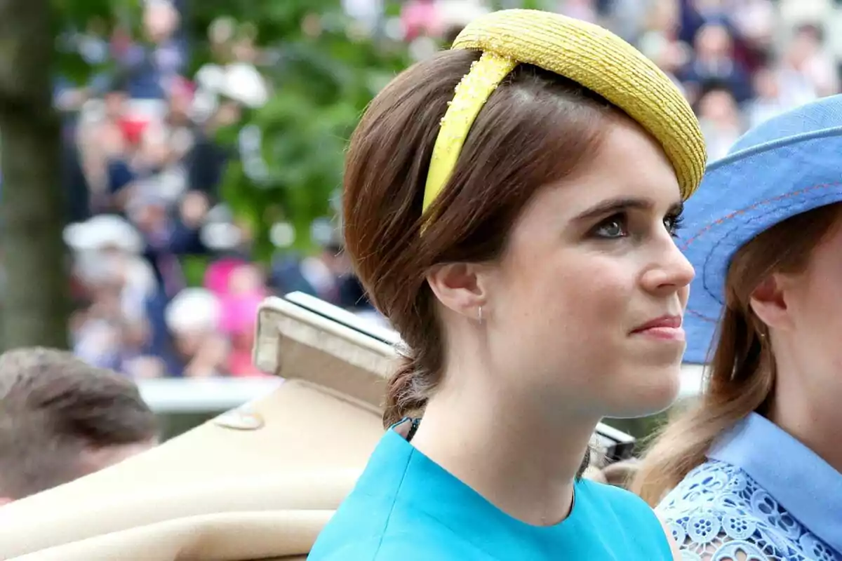 A woman in a blue dress and a yellow hat at an outdoor event.