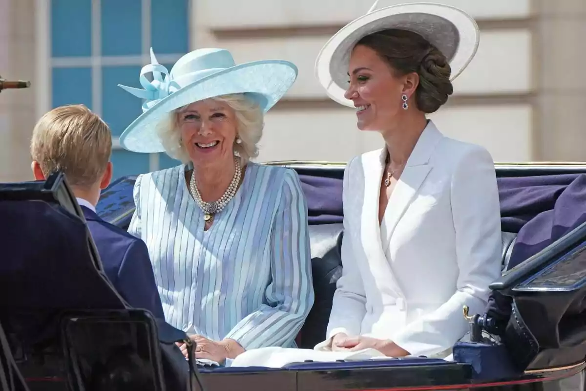 Two elegantly dressed women with hats are sitting in a carriage next to a blond child.