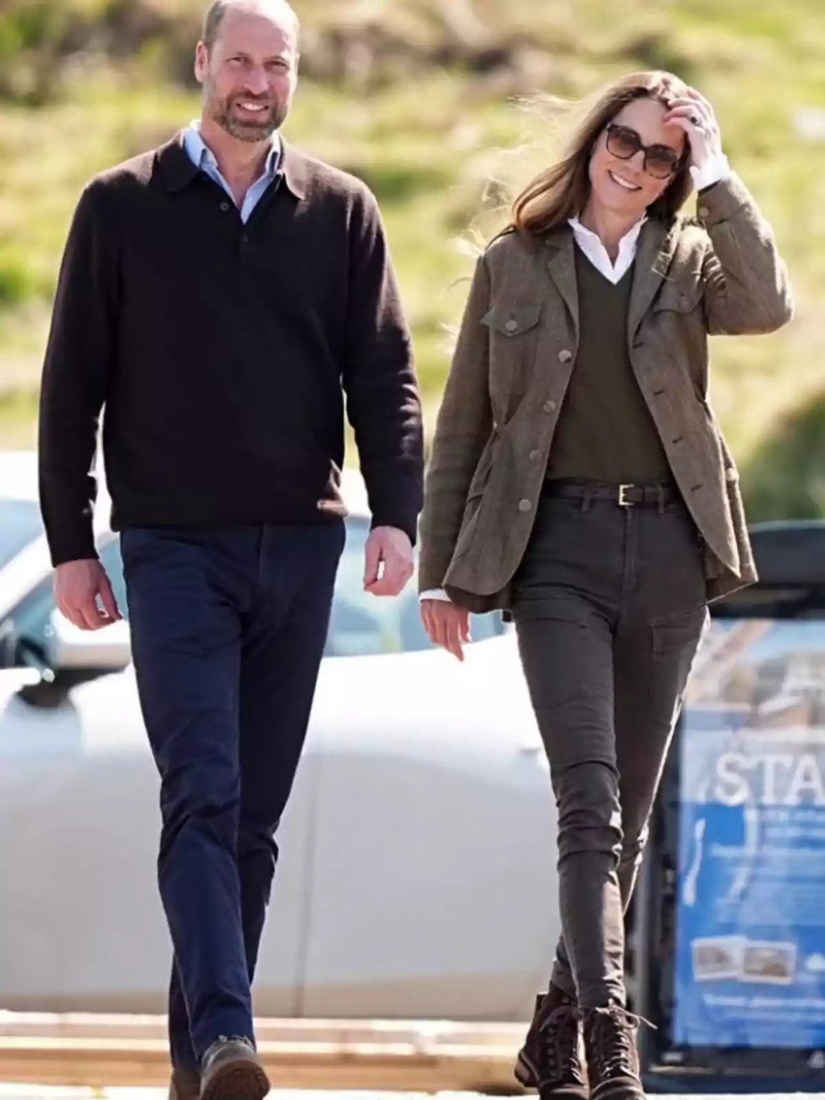 Two people walking outdoors on a sunny day, both wearing casual clothes and seeming to enjoy the moment.