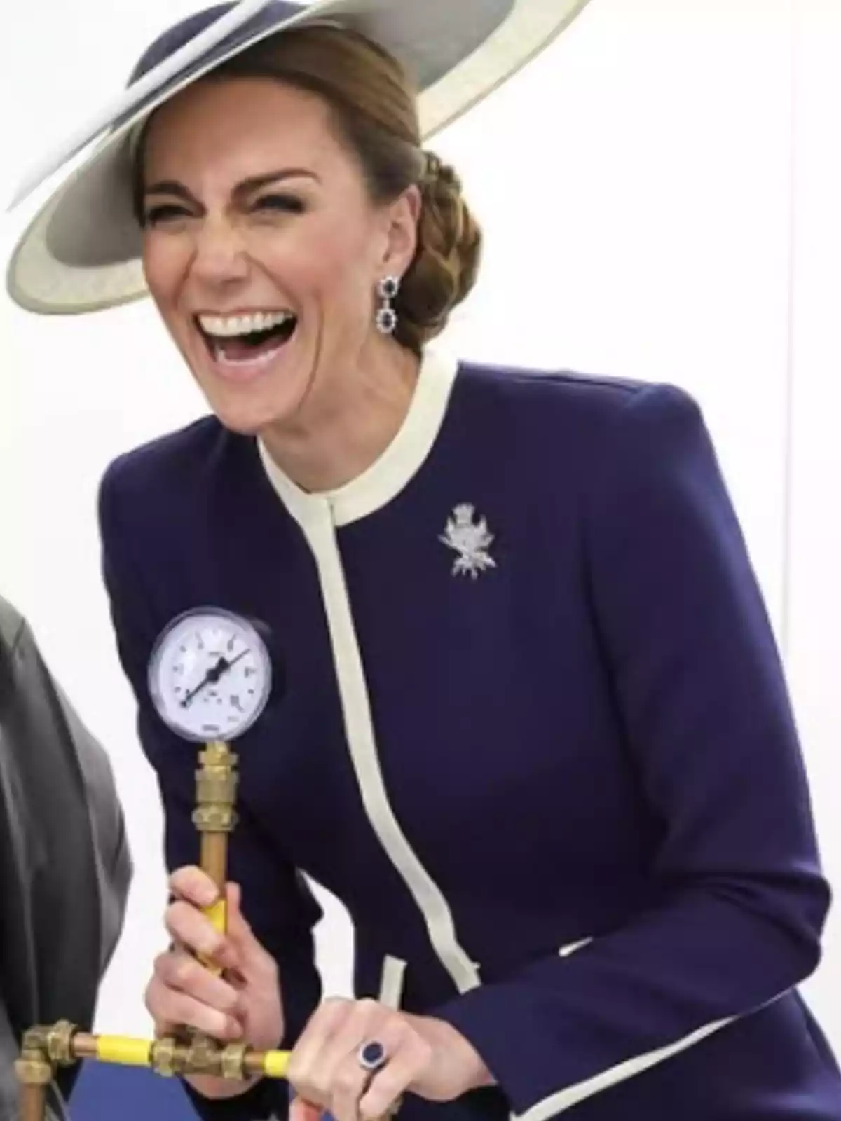 A smiling woman with an elegant hat and a dark blue suit holds a pressure gauge. A smiling woman with an elegant hat and a dark blue suit holds a pressure gauge.