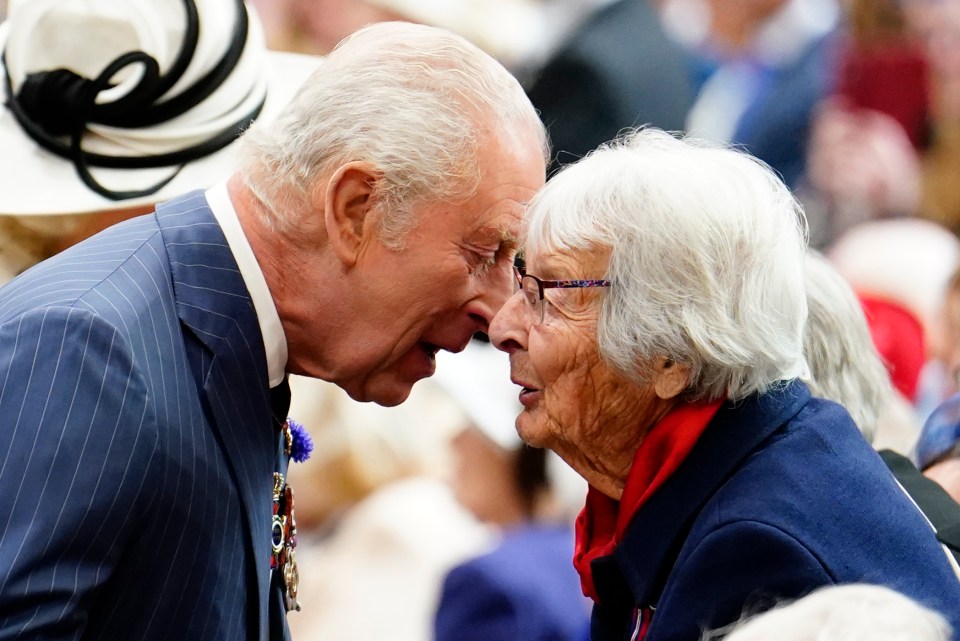 King Charles III speaking to a veteran at a service.
