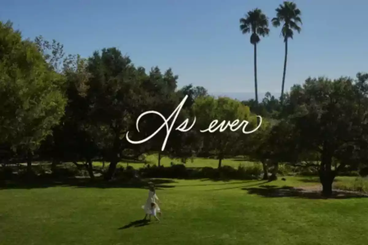 Meghan Markle and Lilibet run through a green field surrounded by trees with two palm trees in the background and the text 