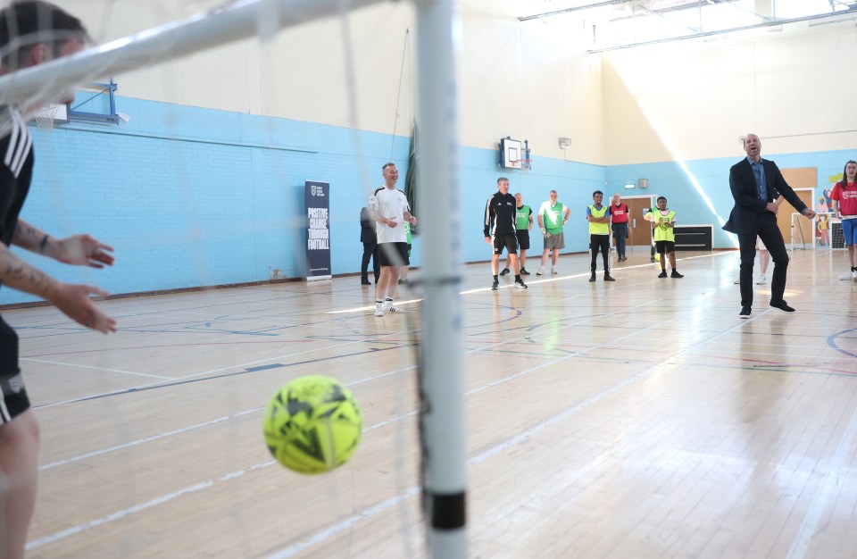 Prince William playing football in a gymnasium.