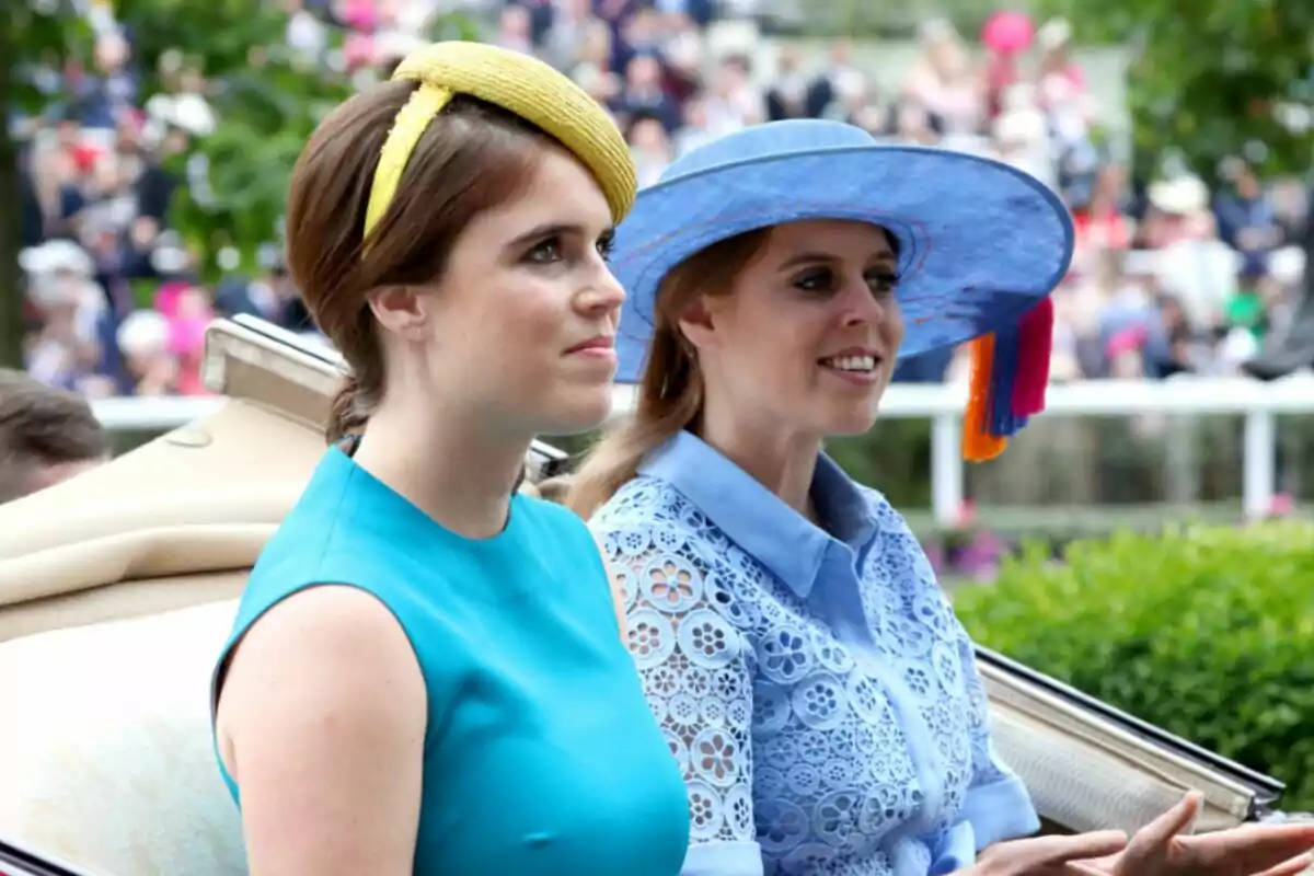 Princesses Eugenie and Beatrice elegantly dressed in colorful hats at an outdoor event.