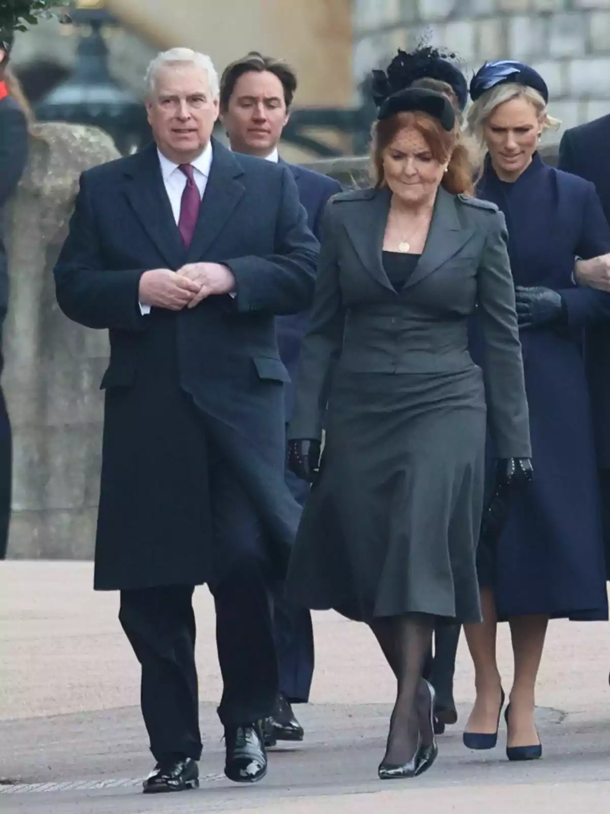 A group of formally dressed people walk down a street, with grey-haired Prince Andrew and red-haired Sarah Ferguson at the front.