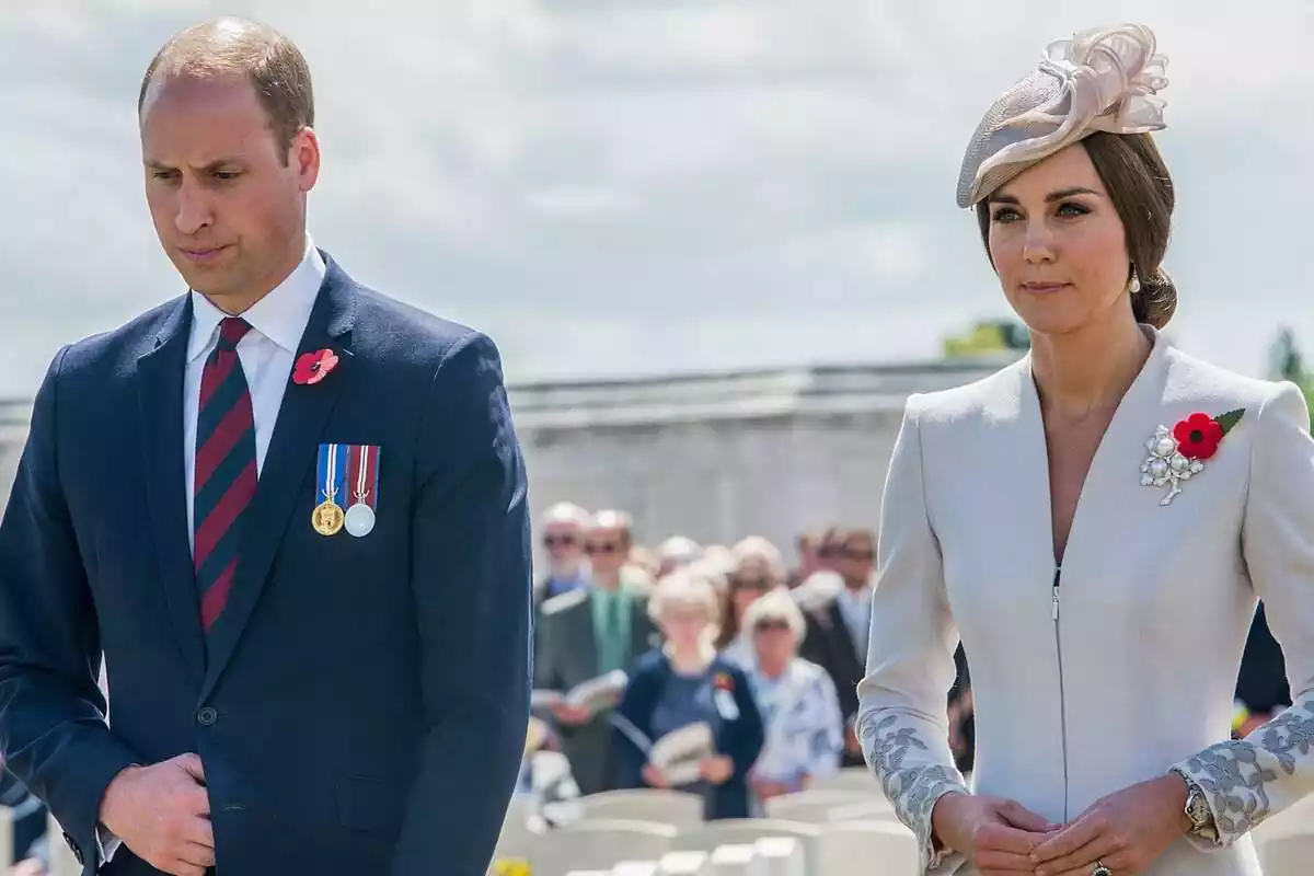 Prince William serious in a blue and red suit and tie next to Kate Middleton dressed in white with a headdress Prince William serious in a blue and red suit and tie next to Kate Middleton dressed in white with a headdress