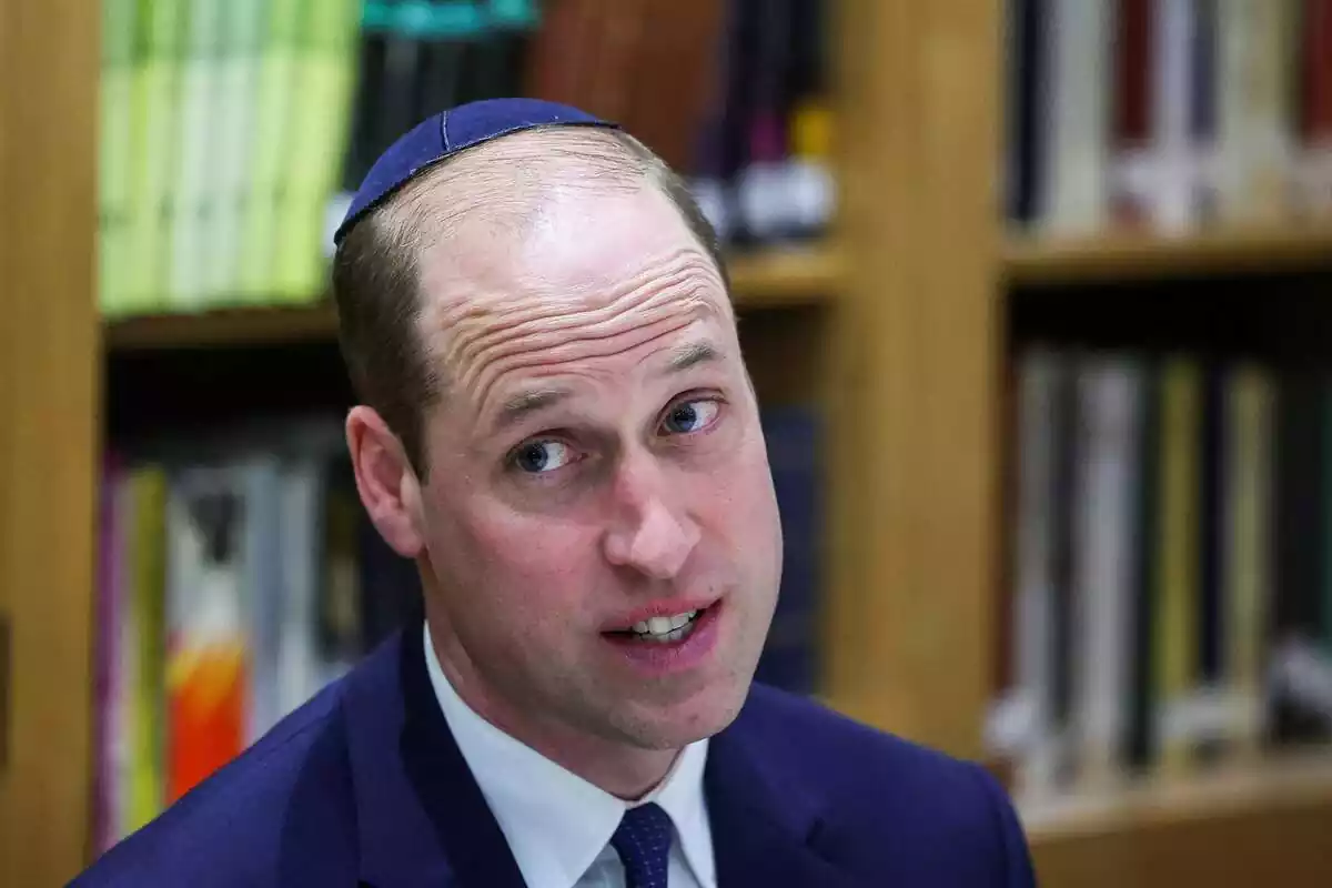 Prince William speaking looking to the side in a blue suit