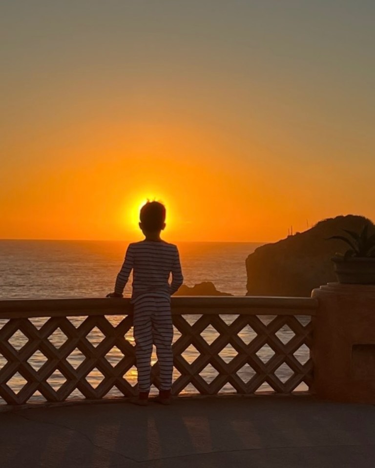 Silhouette of a child watching the sunset over the ocean.
