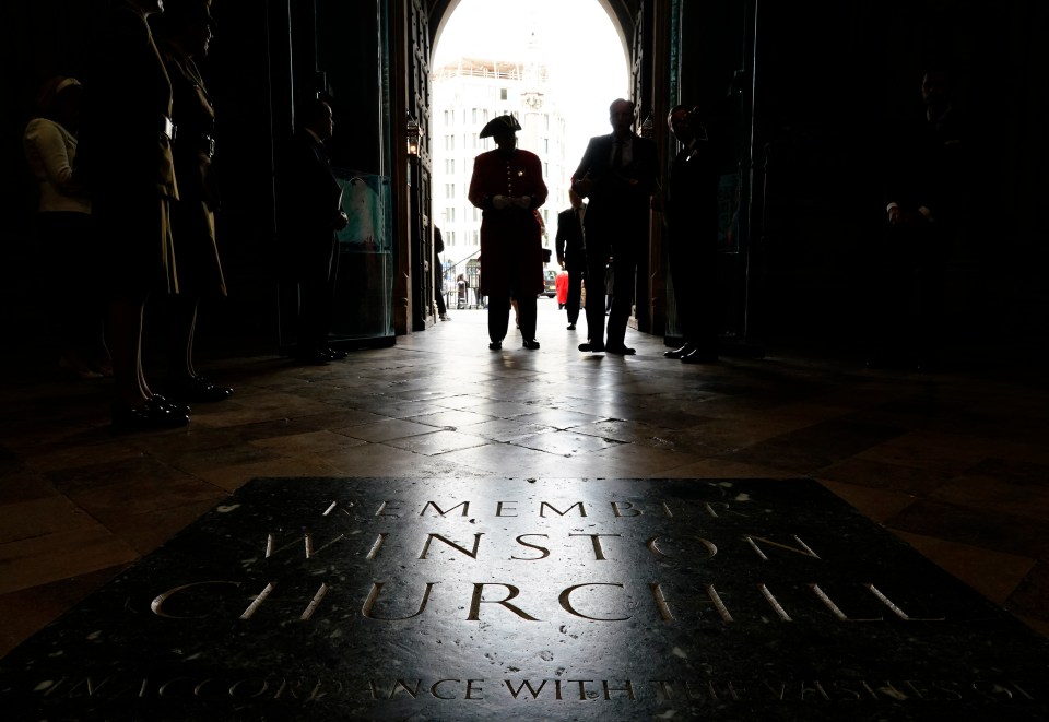 Silhouetted figures at Westminster Abbey's entrance, with a stone inscription for Winston Churchill visible on the floor.