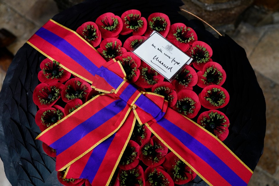 Wreath of red poppies with a purple and red ribbon and a card signed "Charles".