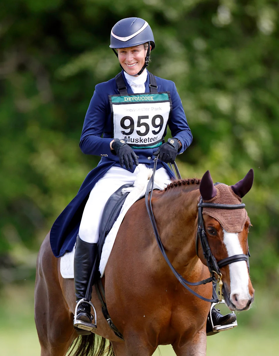Zara Tindall wearing a blue jacket and helmet riding a brown horse
