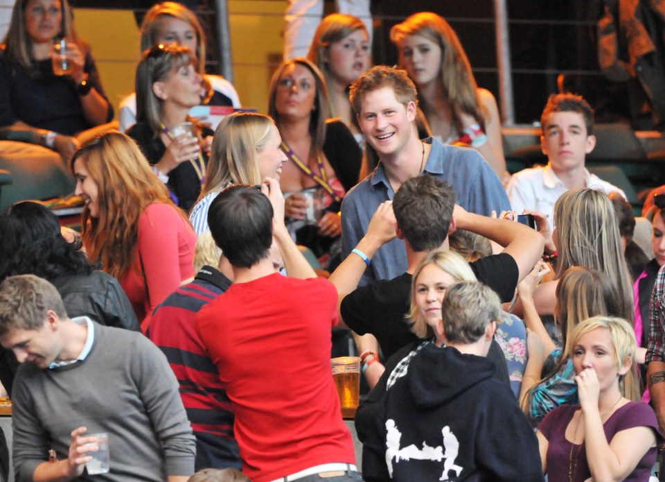 Prince Harry at a concert, surrounded by people.