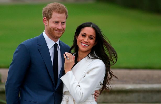 Britain's Prince Harry stands with his fiancée US actress Meghan Markle as she shows off her engagement ring whilst they pose for a photograph in the Sunken Garden at Kensington Palace in west London on November 27, 2017, following the announcement of their engagement.