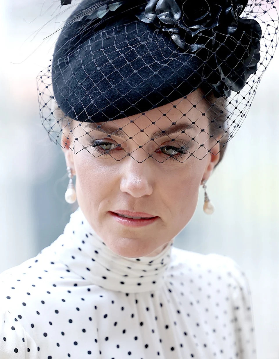 A close-up of Kate Middleton wearing a polka dot dress and a black fascinator.