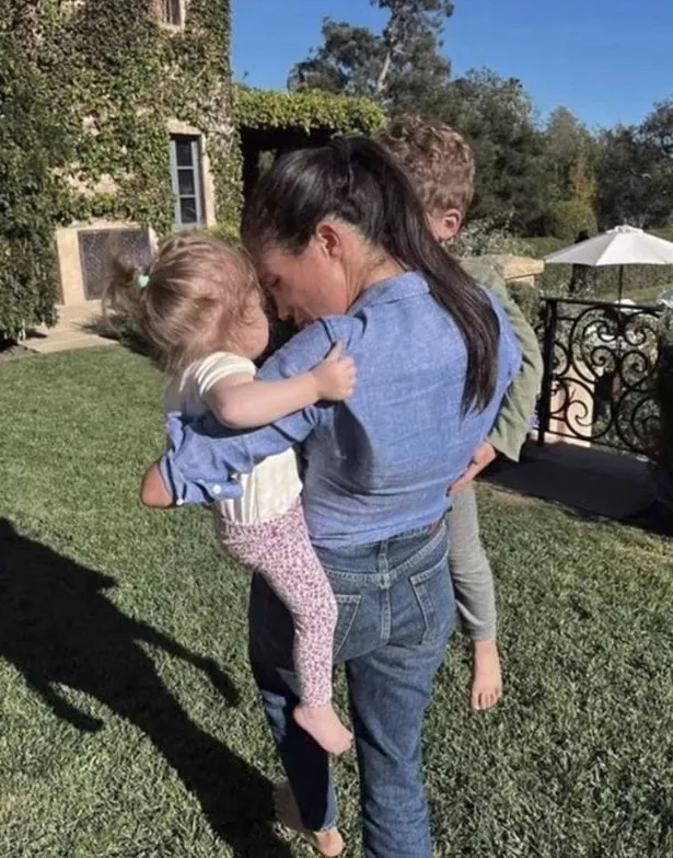 Meghan Markle holding her children Archie and Lilibet on each hip