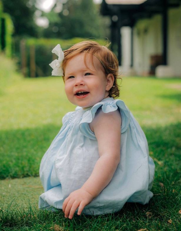 Princess Lilibet wearing a dress sitting on some grass