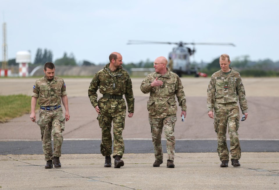 Prince William walking with military personnel at an airfield.