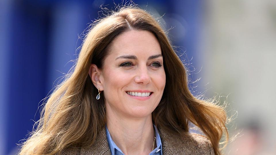 A close-up of Kate Middleton smiling in a brown blazer.